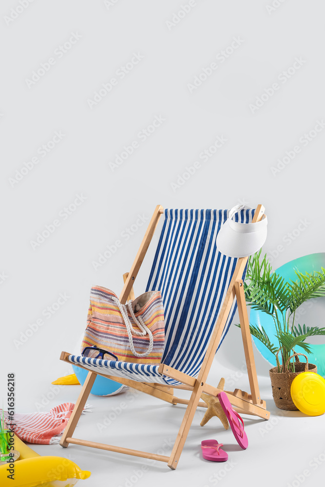 Deckchair with beach accessories and plant on grey background. Travel concept