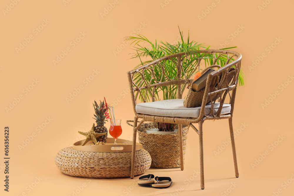 Chair with beach accessories, cocktail, pineapple and plant on pale orange background. Travel concep