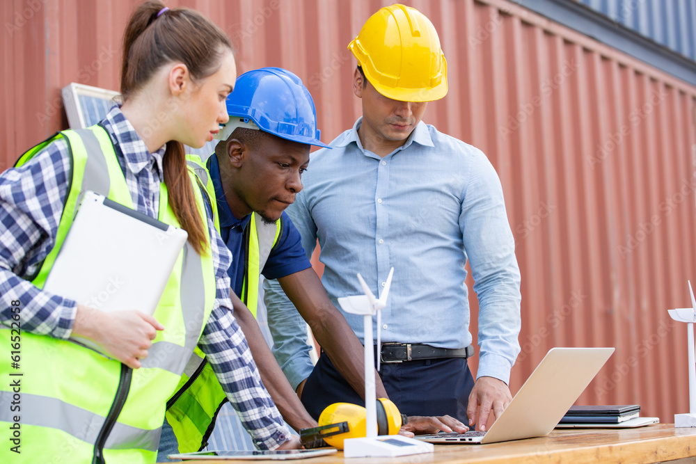 Engineer worker team discussing of solar energy from wind turbine model and laptop at construction s