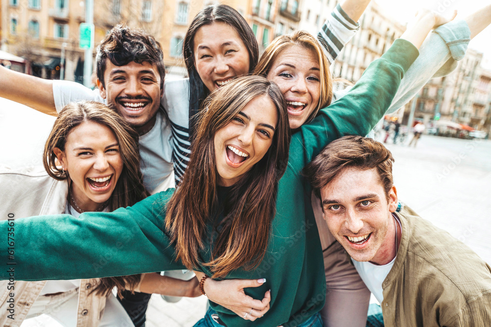 Multicultural young people smiling at camera outside - Millenial friends having fun hanging on city 