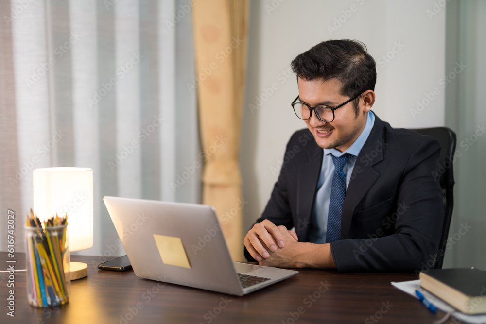 A businessman having online meeting with laptop in private office.