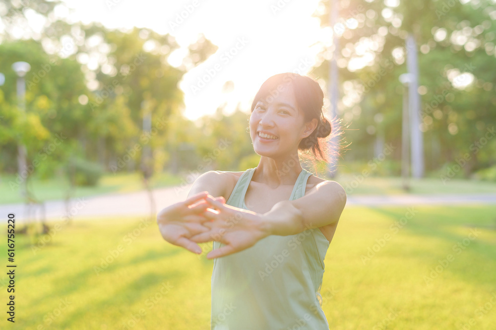 Female jogger. Fit young Asian woman with green sportswear stretching muscle in park before running 