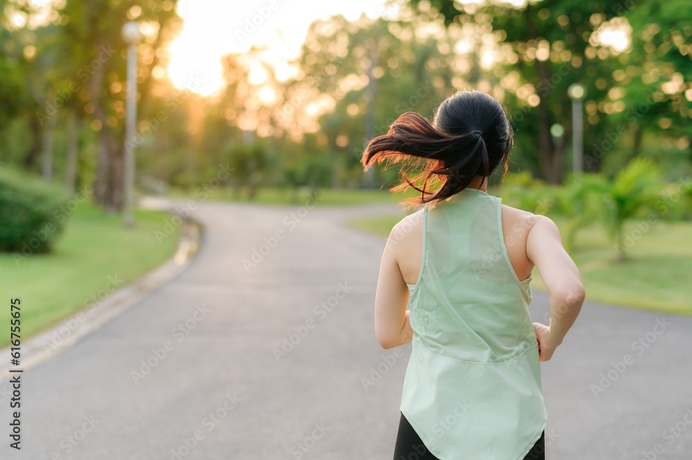 Fit Asian young woman jogging in park smiling happy running and enjoying a healthy outdoor lifestyle