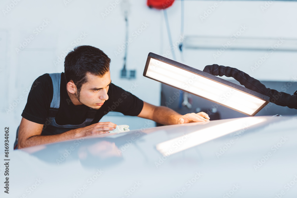 Car mechanic working to remove dent in workshop.