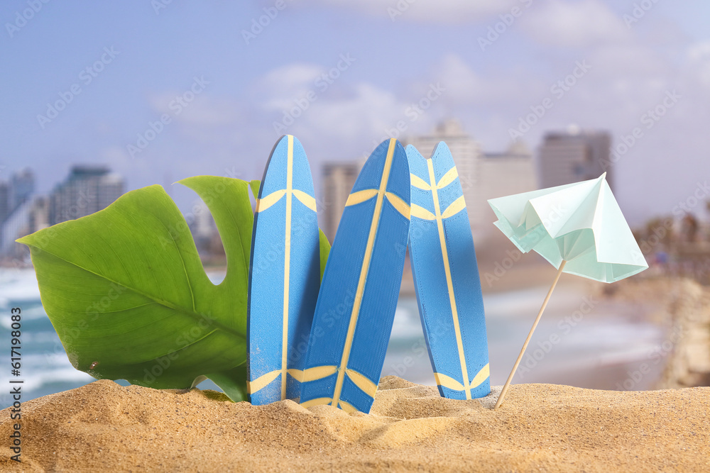 Small surfboards, umbrella and tropical leaf on beach sand