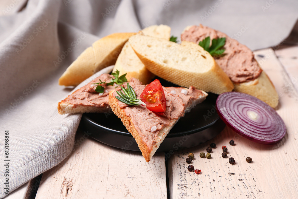 Plate of delicious sandwiches with pate on light wooden background