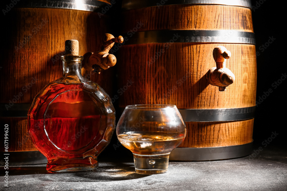 Barrels with bottle and glass of cold rum on wooden table