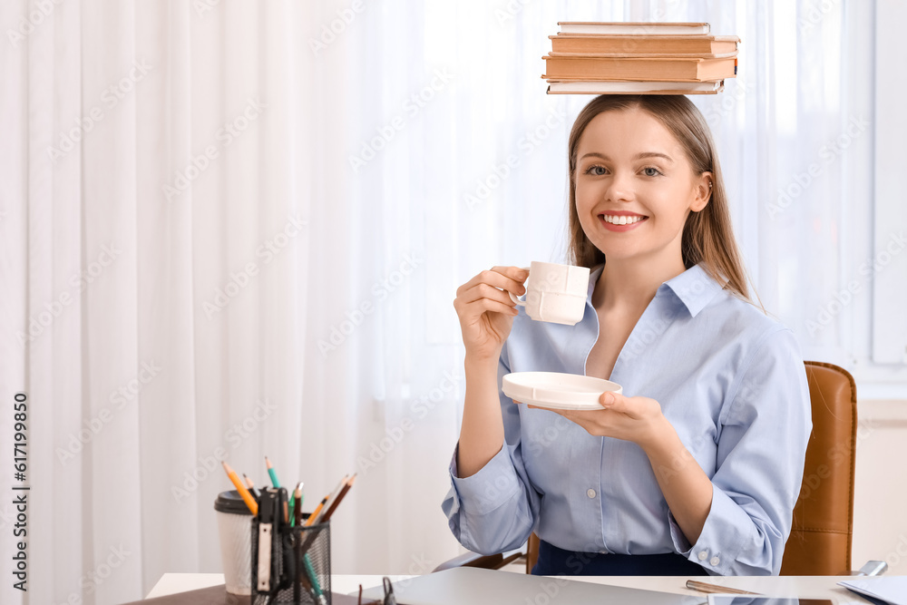 Young businesswoman with books drinking coffee in office. Balance concept