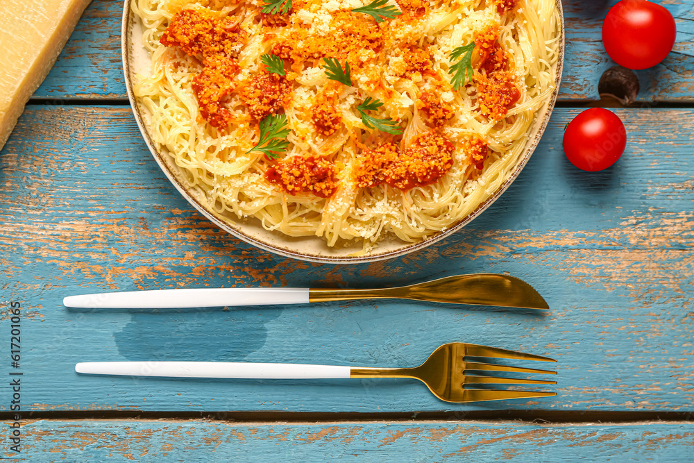 Plate of tasty Italian pasta with Parmesan cheese on blue wooden background, closeup