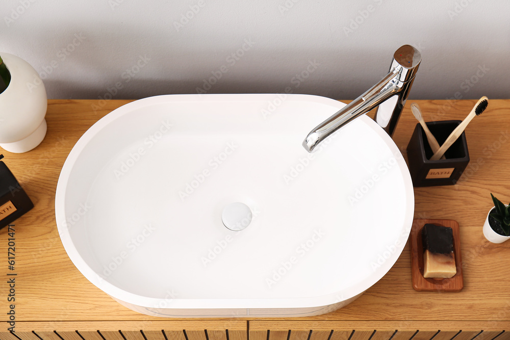 White sink with bath accessories on table in room, top view