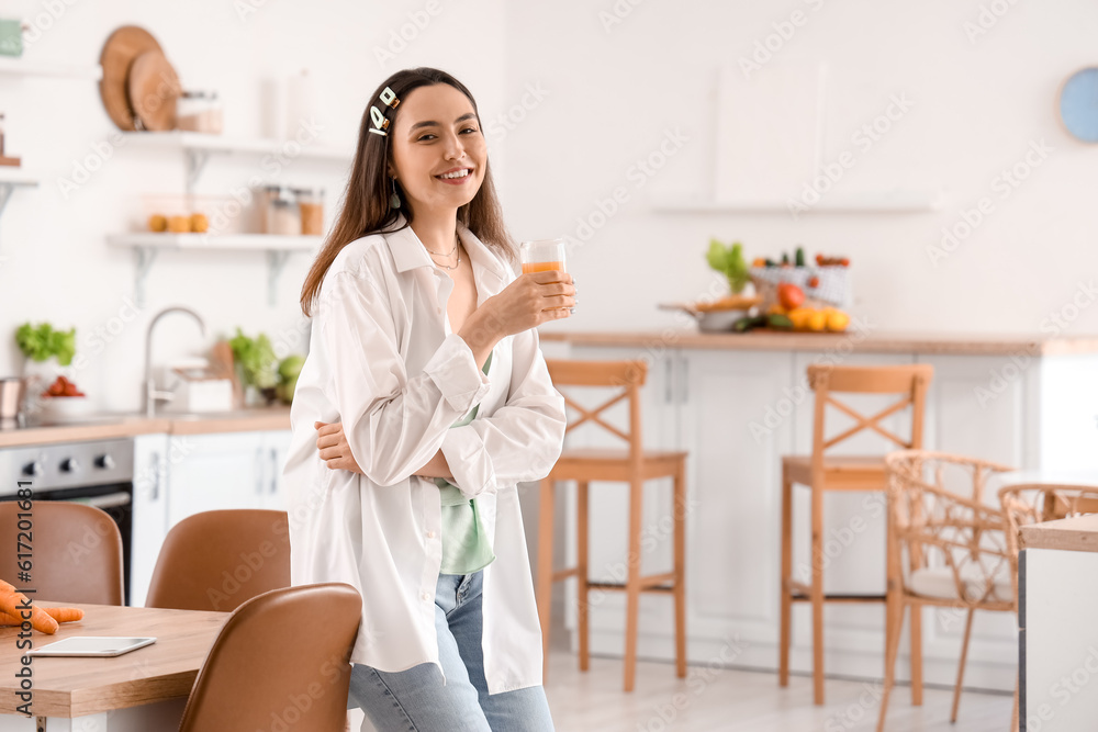 Young woman with glass of vegetable juice in kitchen