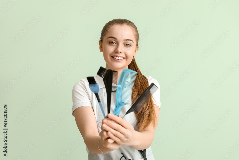 Female hairdresser with brushes on green background