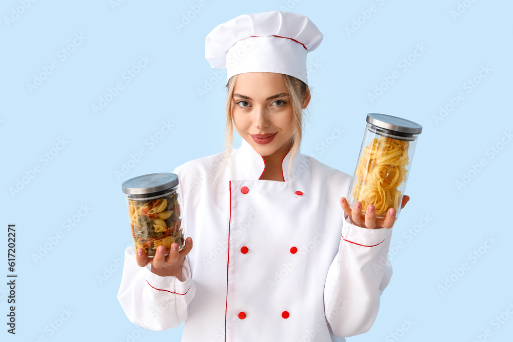 Female chef with raw pasta on blue background