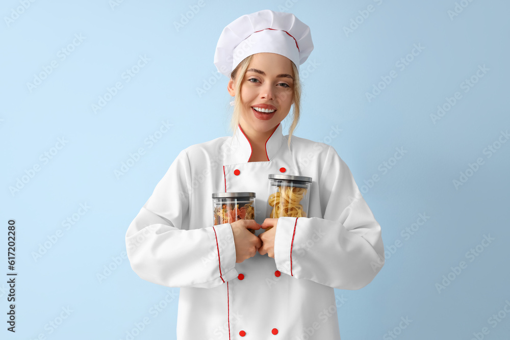 Female chef with raw pasta on blue background