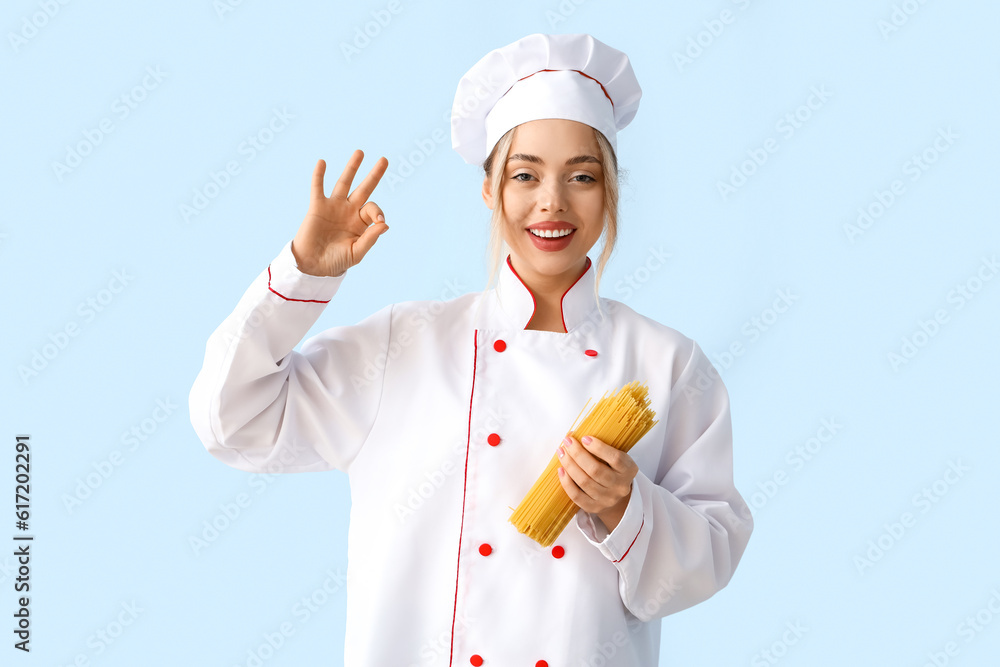 Female chef with raw pasta showing OK on blue background