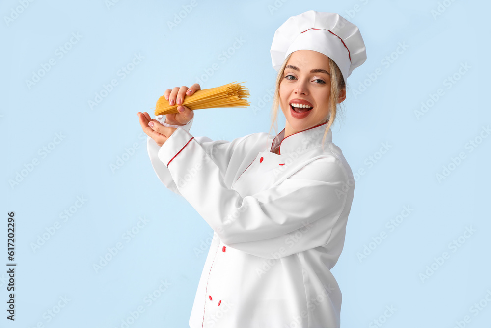 Female chef with raw pasta on blue background