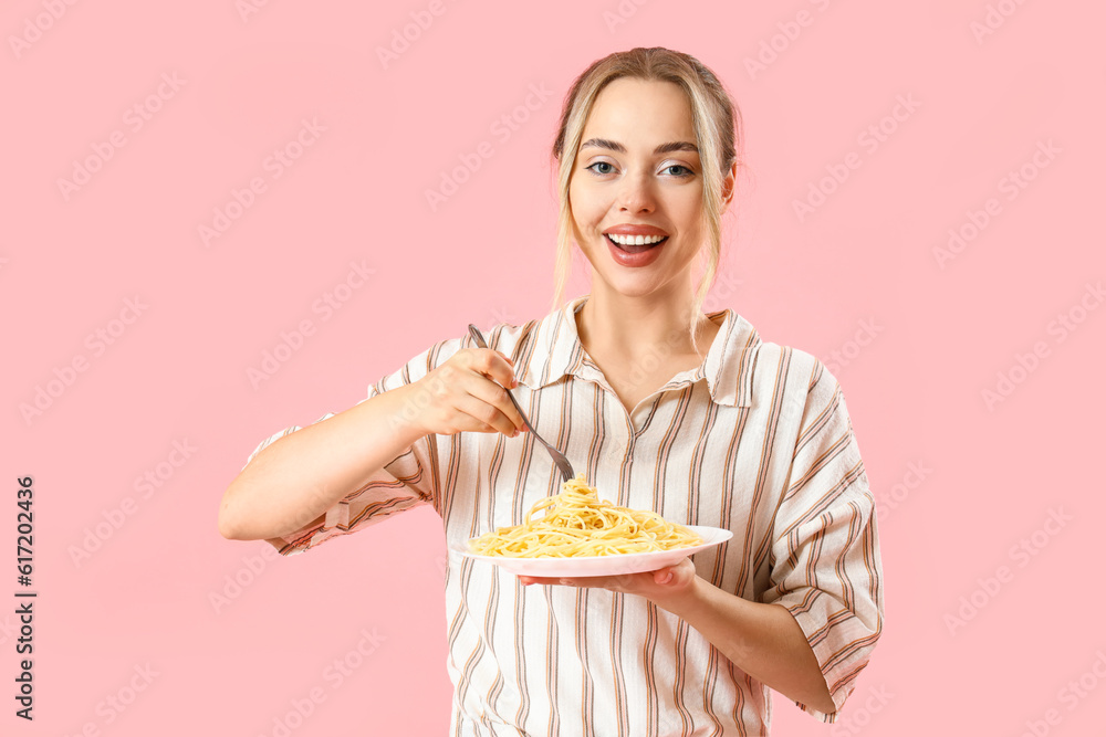 Young woman with tasty pasta on pink background