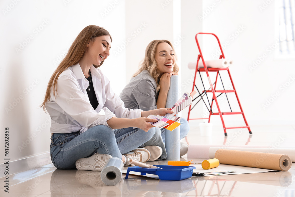 Young women with wallpaper roll and paint color palettes at home