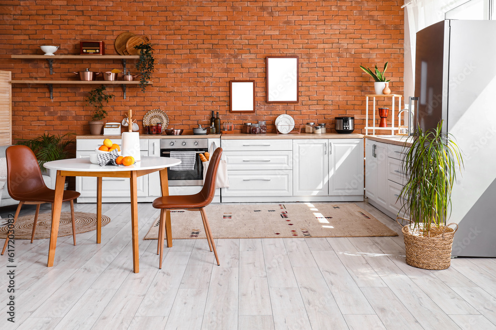 Interior of kitchen with stylish fridge, counters, shelves, table and chairs