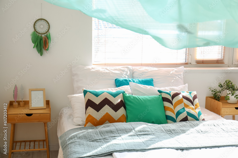 Interior of modern bedroom with bed, bedside table and dream catcher hanging on white wall