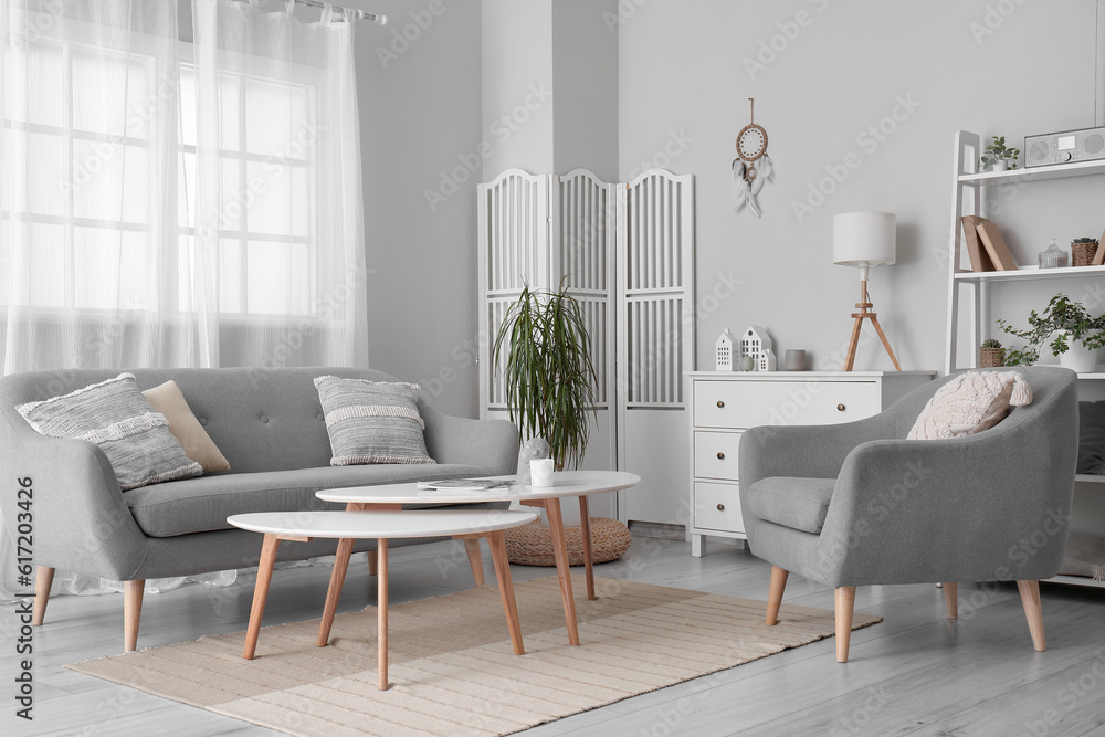 Interior of modern living room with sofa, armchair and dream catcher hanging on light wall