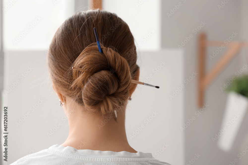 Female artist with brushes in her hair, back view