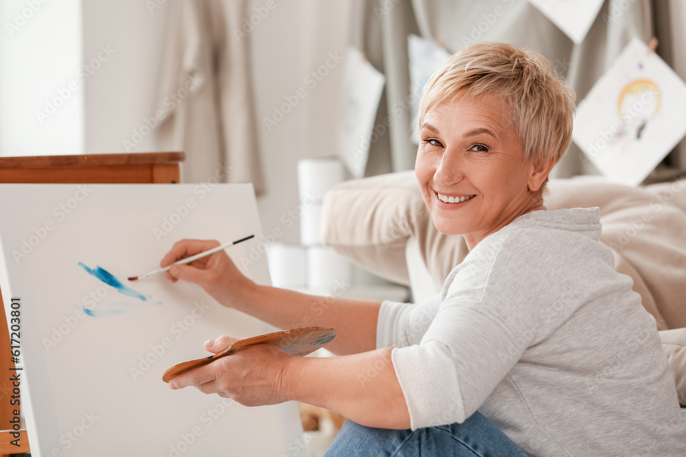 Mature female artist painting picture in  workshop