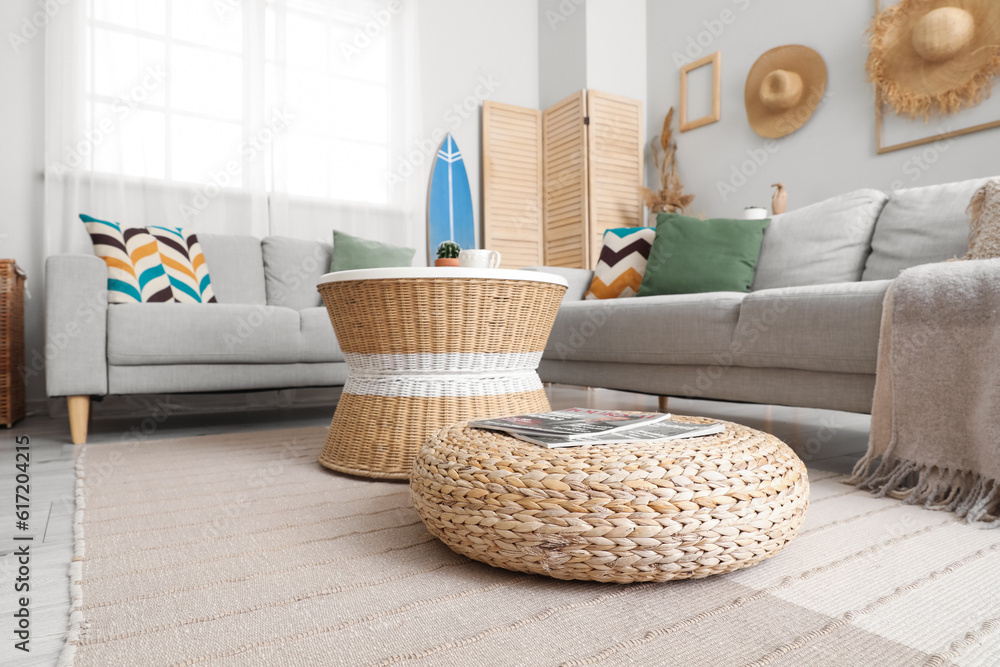 Interior of light living room with surfboard, table and sofas