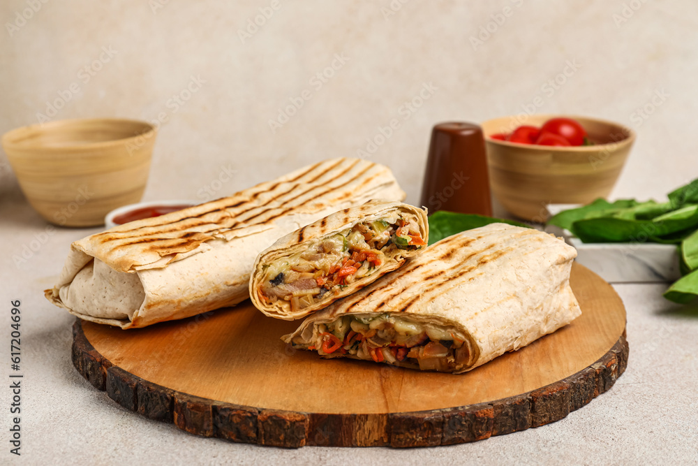 Board of tasty shawarma and bowl with tomatoes on white table