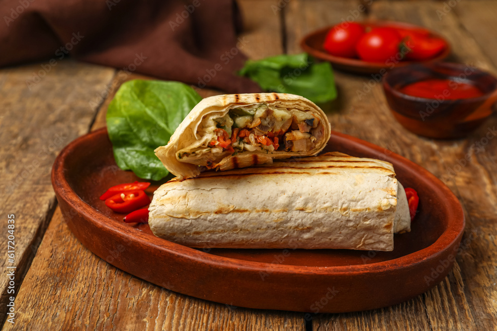 Plate with tasty shawarma and spinach on wooden background