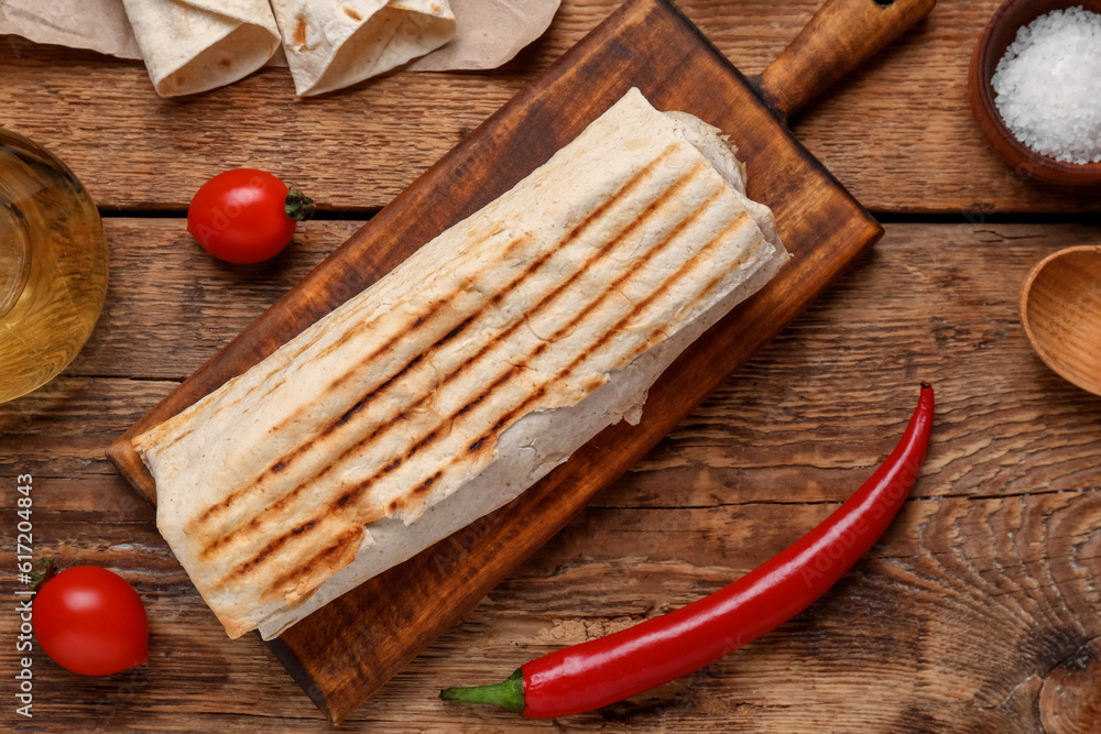 Board of tasty shawarma with tomatoes on wooden background