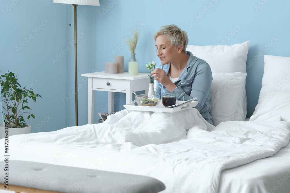 Mature woman having breakfast in bed