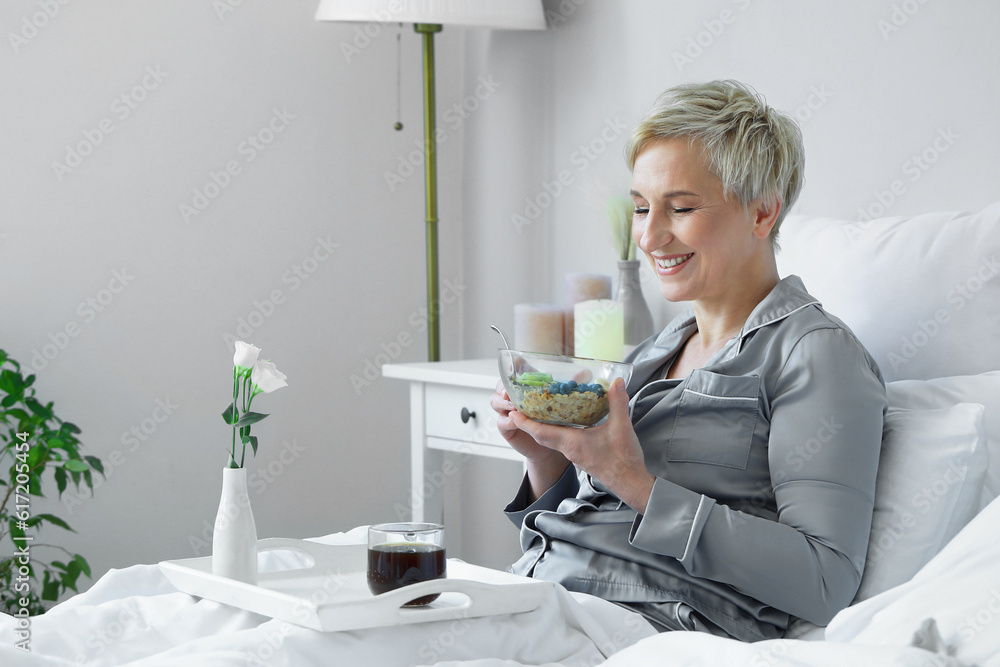 Mature woman having breakfast in bed