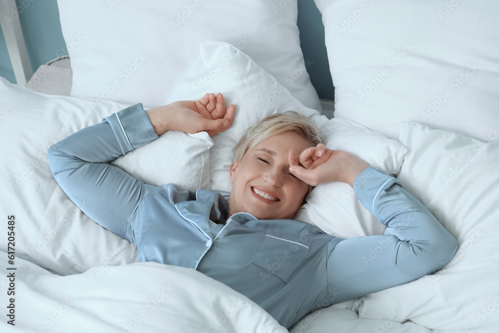 Happy mature woman lying in bed