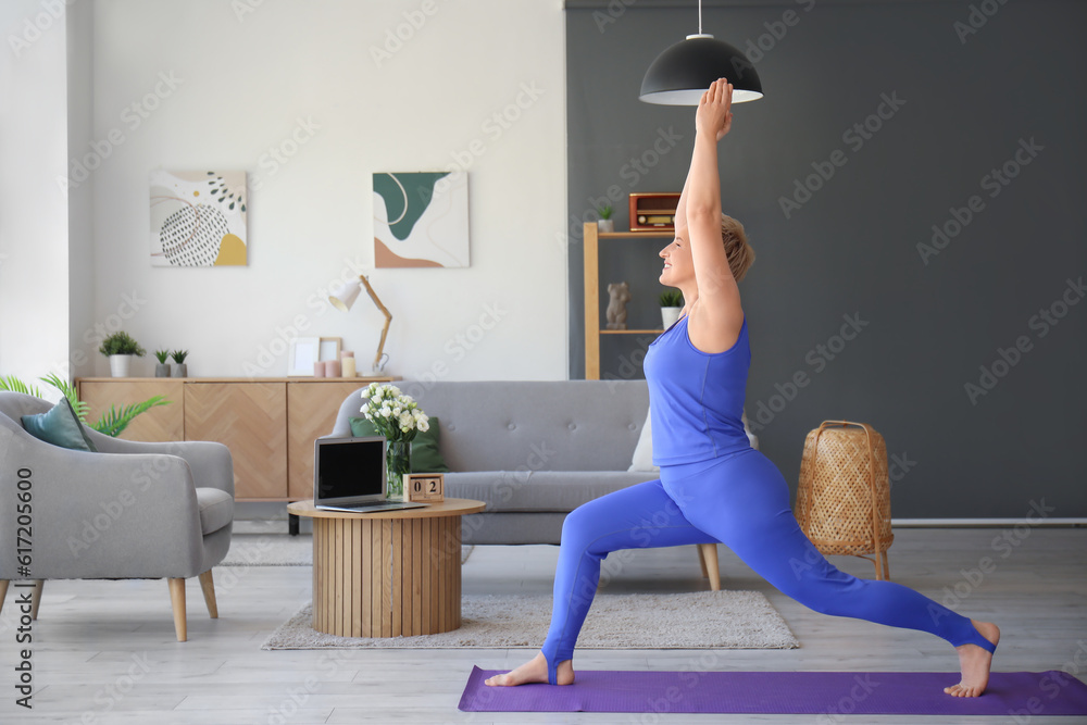 Sporty mature woman doing yoga at home