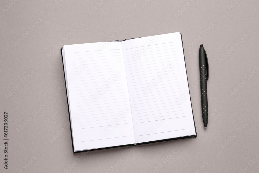 Blank open notebook and pen on grey background