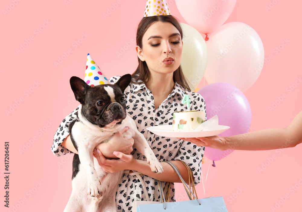 Young woman with her French bulldog celebrating Birthday on pink background