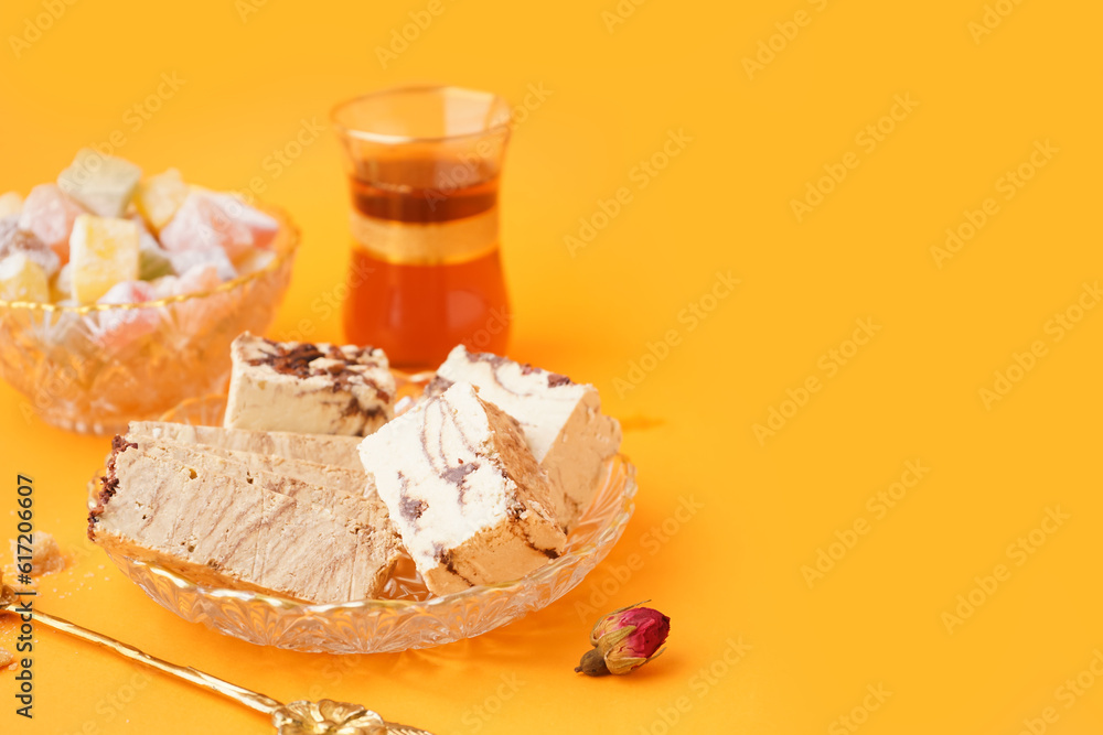 Bowl with pieces of tasty marble halva on orange background