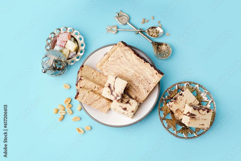 Plates with pieces of tasty marble halva and Turkish delight on blue background