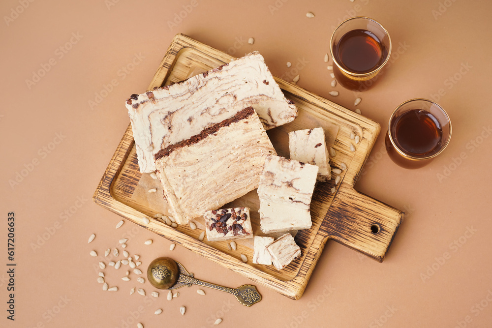 Pieces of tasty marble halva and glasses with Turkish tea on brown background