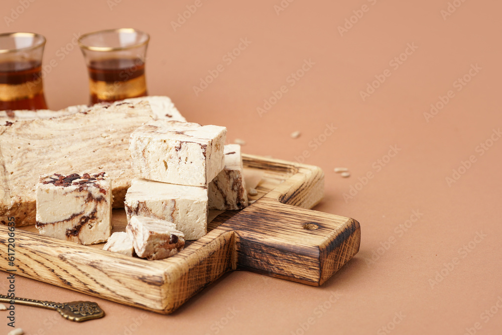 Wooden board with pieces of tasty marble halva on brown background