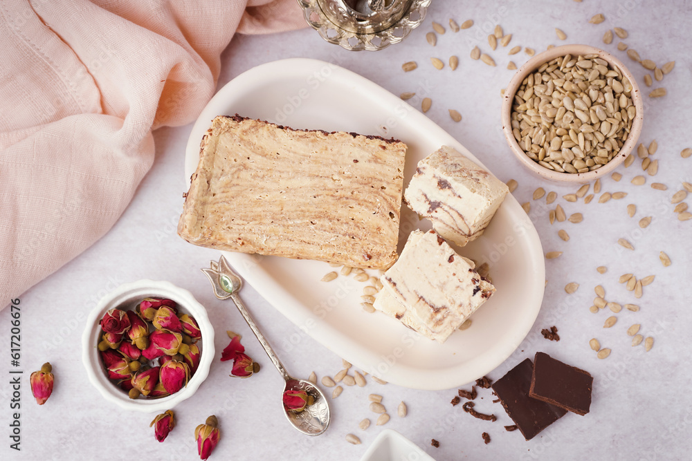 Plate with pieces of tasty marble halva on light background