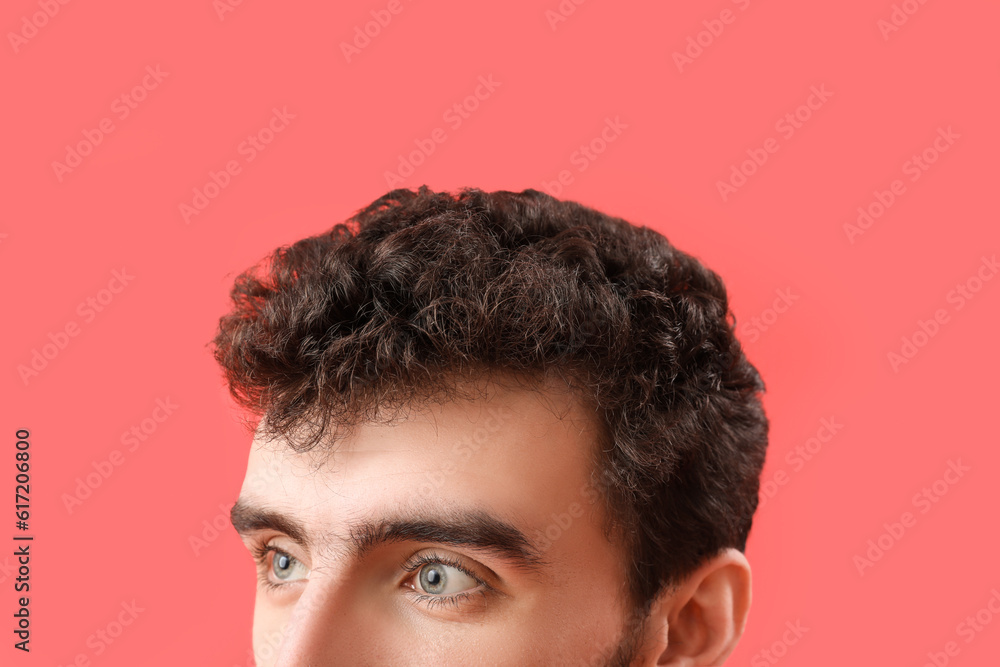 Young brunette man with stylish hairdo on red background, closeup