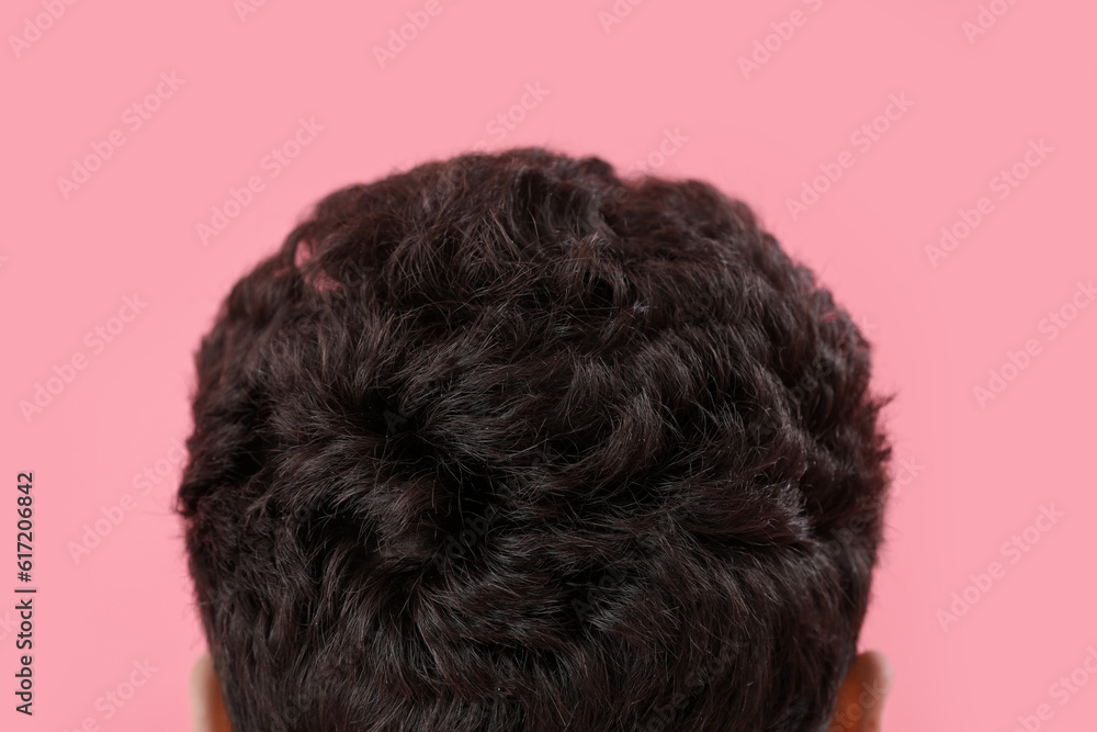 Young brunette man with stylish hairdo on pink background, back view