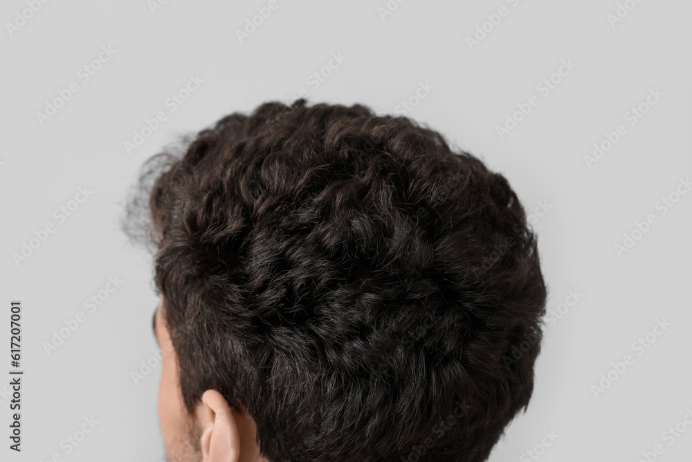 Young brunette man with stylish hairdo on light background, closeup