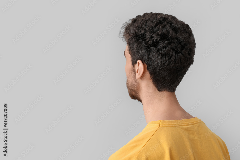 Young brunette man with stylish hairdo on light background, closeup