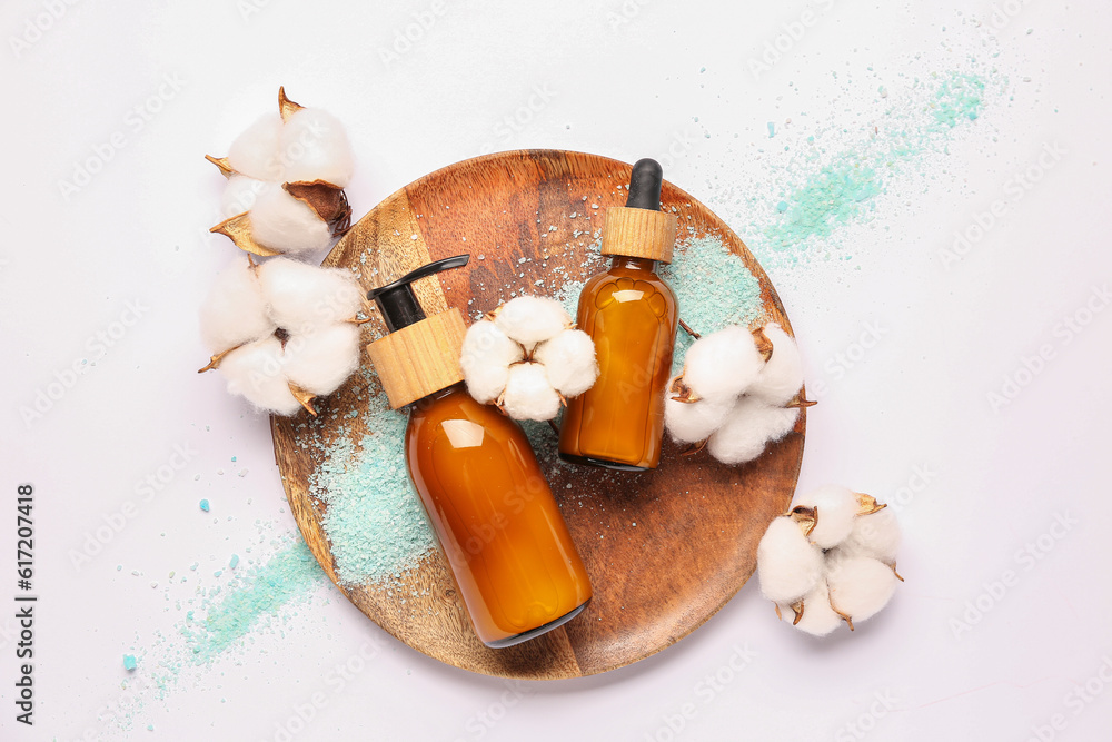 Composition with cosmetic products, sea salt and cotton flowers on white background