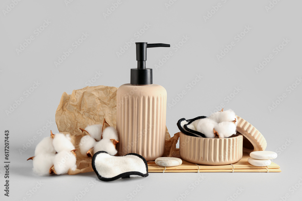 Bottle of cosmetic product, cotton pads and flowers on white background