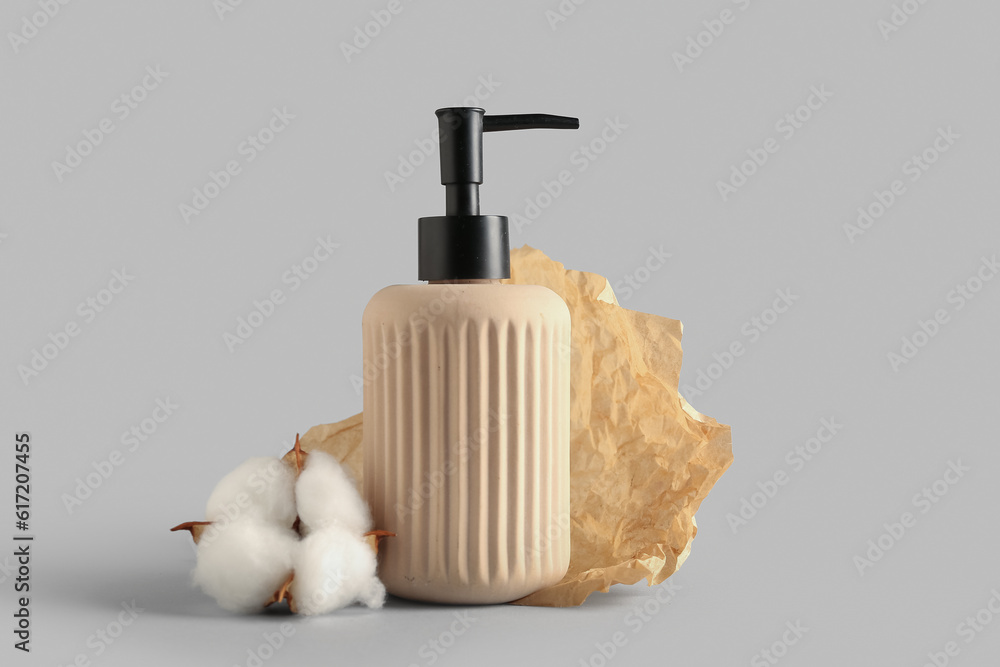 Bottle of cosmetic product and cotton flower on white background