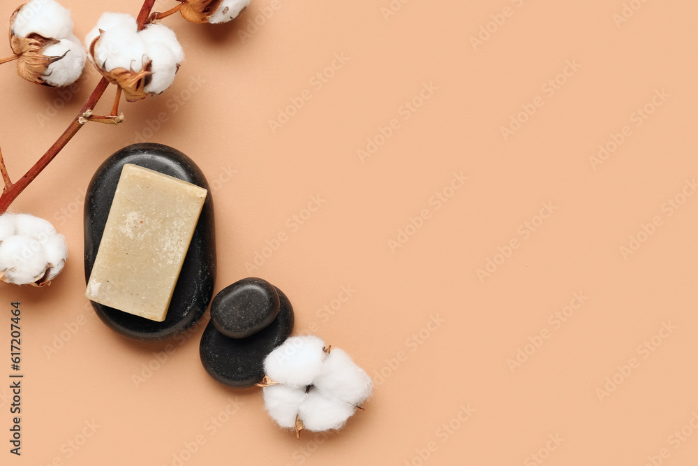 Soap bar, spa stones and cotton branch on color background